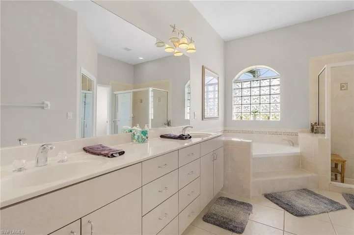 Bathroom featuring a stall shower, double vanity, tile patterned flooring, and a bath
