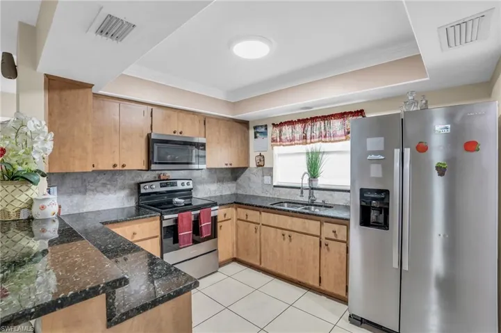 Kitchen with crown molding, sink, a raised ceiling, appliances with stainless steel finishes, and backsplash