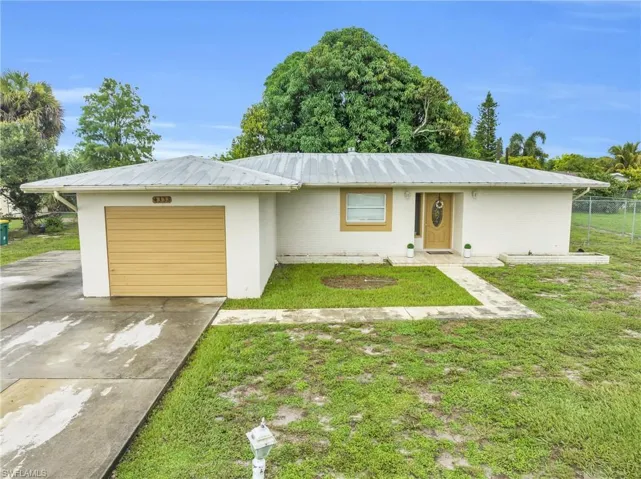 Ranch-style house featuring a garage and a front yard