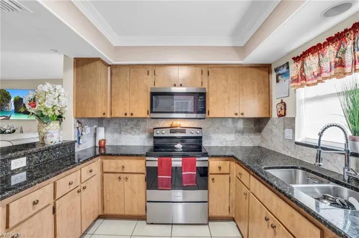 Kitchen featuring tasteful backsplash, crown molding, appliances with stainless steel finishes, and sink