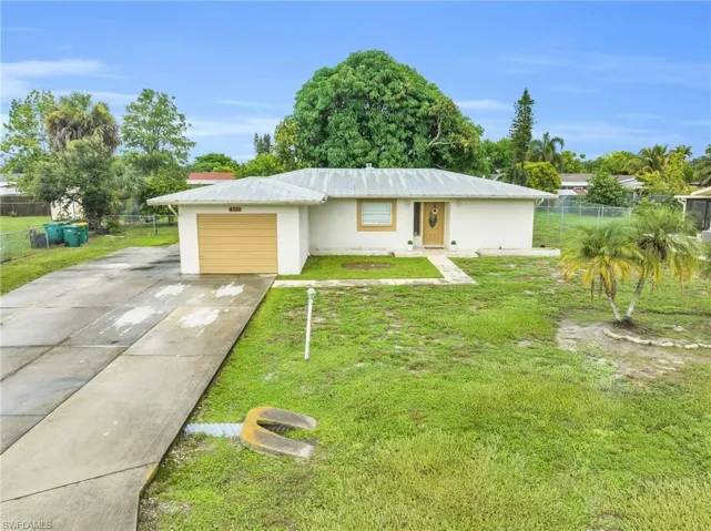 Single story home featuring a garage and a front lawn