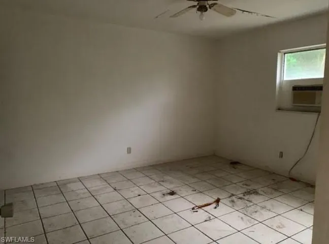 Unfurnished room featuring light tile patterned flooring, a ceiling fan, and cooling unit