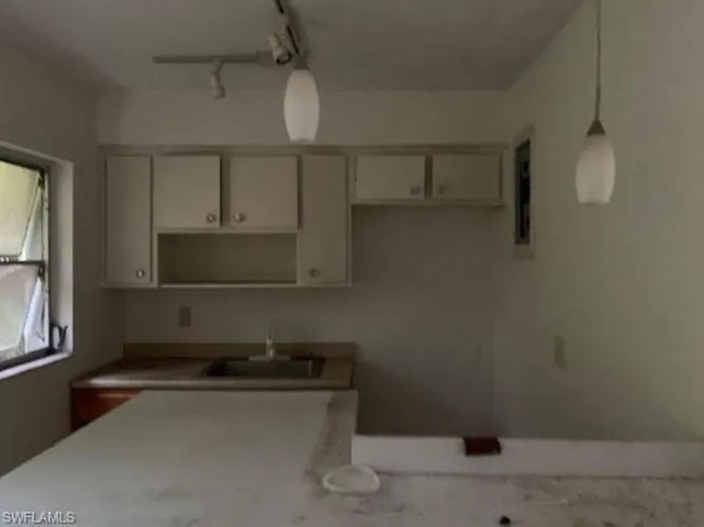 Kitchen with light countertops, pendant lighting, and track lighting