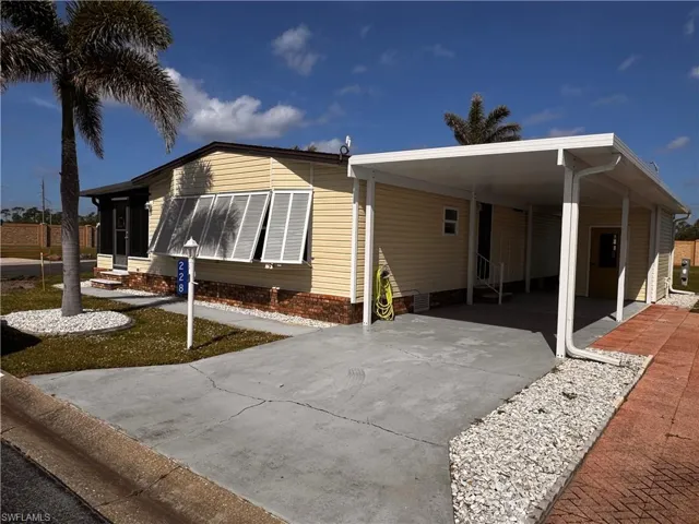 View of side of home featuring driveway, entry steps, and a carport