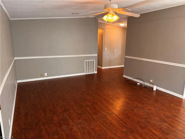 Empty room featuring baseboards, visible vents, a ceiling fan, and wood finished floors