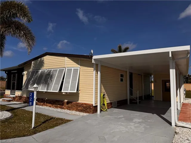 View of side of property with driveway, entry steps, and a carport