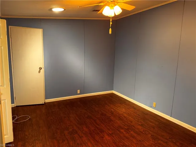 Unfurnished room featuring baseboards, wood finished floors, ceiling fan, and ornamental molding