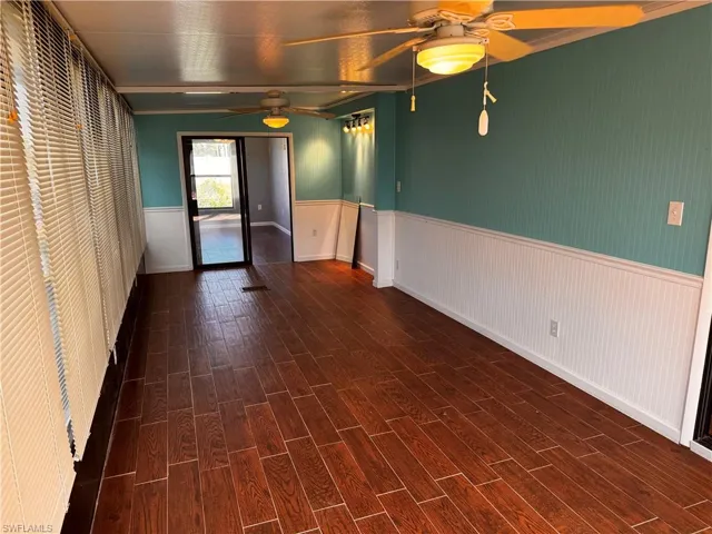 Spare room featuring a ceiling fan, wood finished floors, and wainscoting