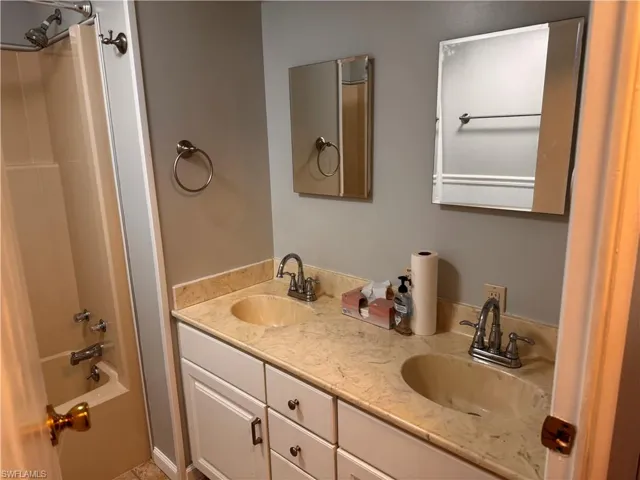 Full bathroom with double vanity, a sink, and shower / tub combination