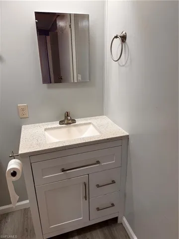 Bathroom featuring vanity, baseboards, and wood finished floors