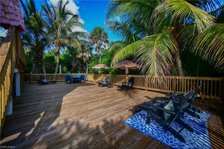 Expansive wood deck with a slatted wood railing, surrounded by mature palm trees and lush foliage