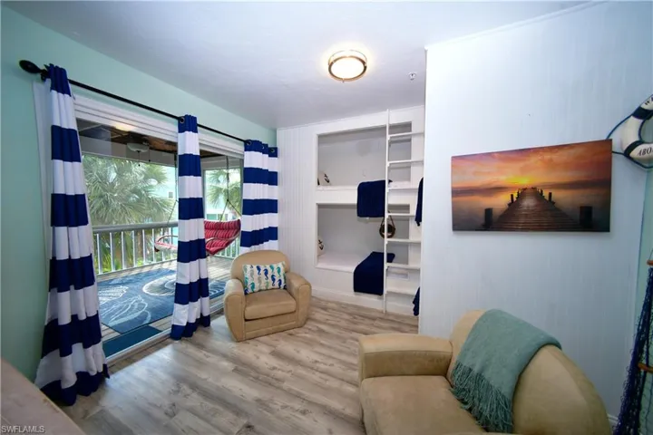 Interior space featuring built-in bunk beds with ladders, wood-finish flooring, and a sliding glass door opening to a screened balcony