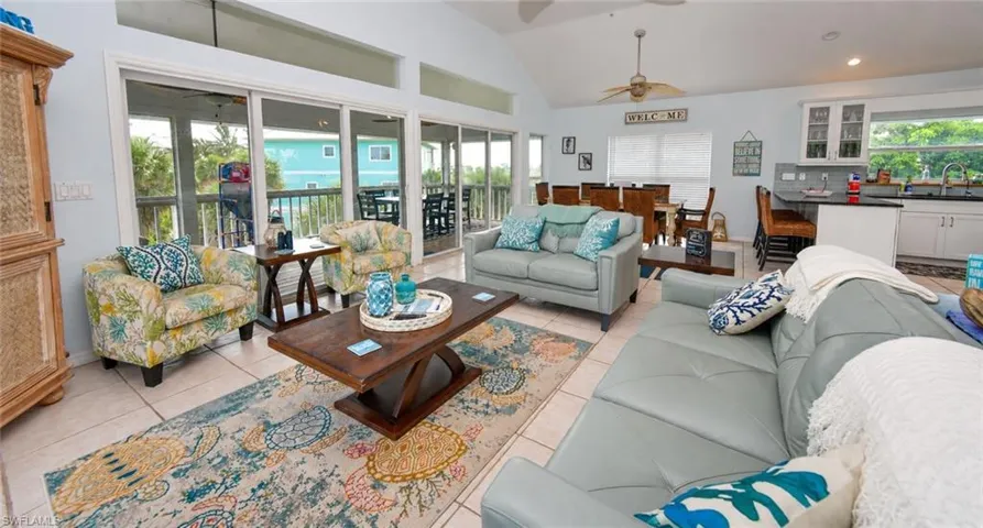 Vaulted ceiling, ceramic tile flooring, extensive triple-pane sliding glass doors, and kitchen cabinetry with integrated glass-front upper displays