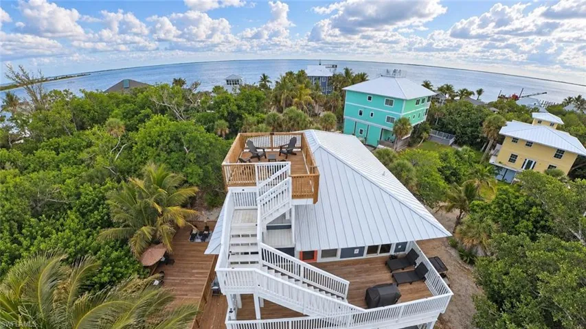 Multi-level wood decking featuring a rooftop observation deck, white metal roofing, and exterior wooden staircases