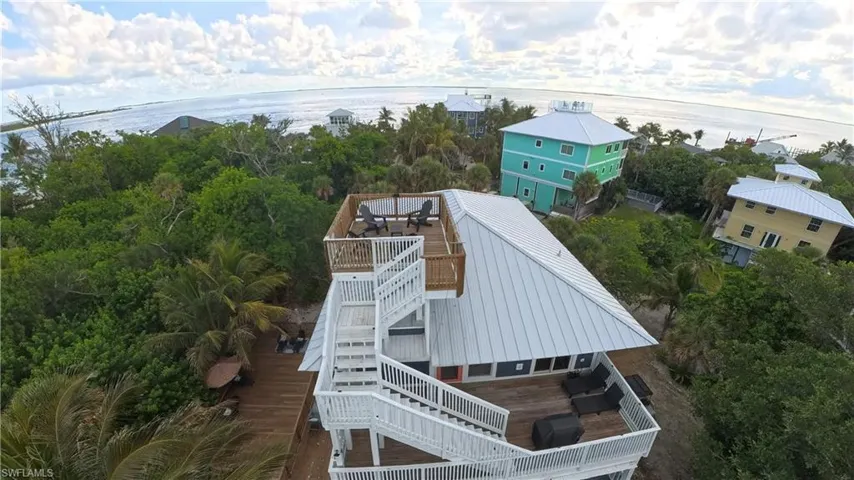 Coastal property featuring multiple outdoor deck spaces, a rooftop deck with seating, and a metal roof