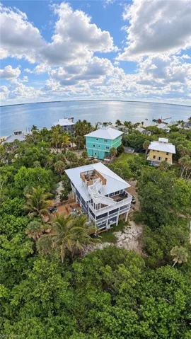 Multi-level residence featuring a metal roof, exterior staircase, elevated deck, and a top-level observation platform nestled within a coastal landscape