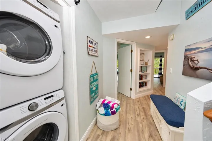 Stacked washer and dryer unit, wood-finish flooring, and built-in recessed wall shelving