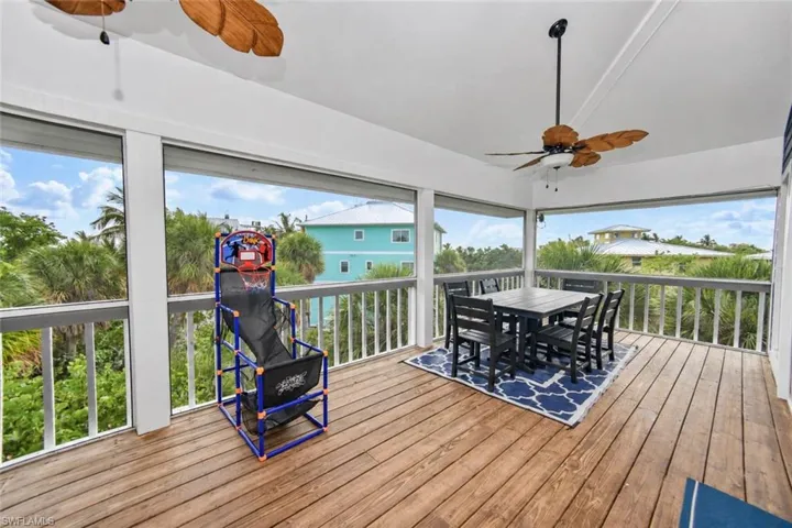 Screened-in deck featuring wood-finish flooring, white railing, and dual ceiling fans