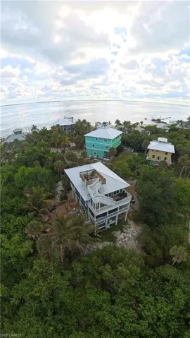 Elevated coastal residence featuring multiple balconies, a rooftop deck, and a metal roof