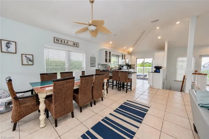 Open-concept interior featuring vaulted ceilings, recessed lighting, tile flooring, and a kitchen island with bar seating