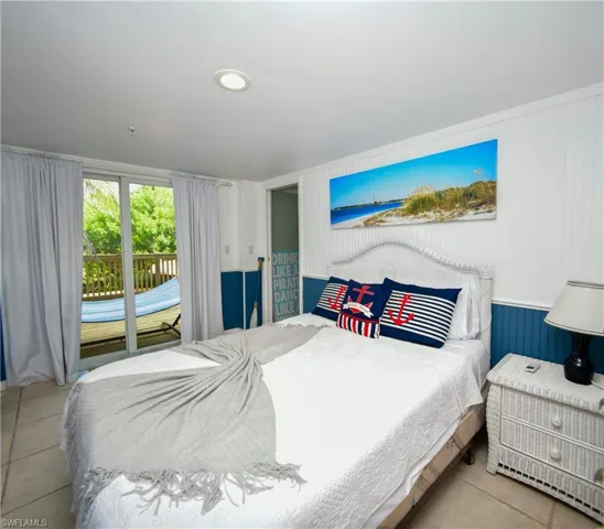Bedroom featuring tile flooring, white beadboard wall paneling, recessed lighting, and sliding glass doors leading to an outdoor deck