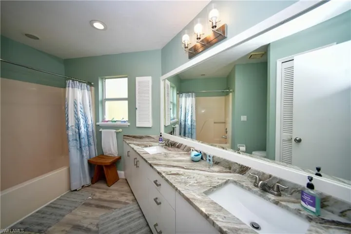 Bathroom featuring an extended double vanity with integrated sinks and stone-finish countertops