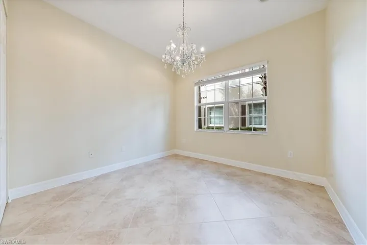 Tiled empty room featuring a notable chandelier