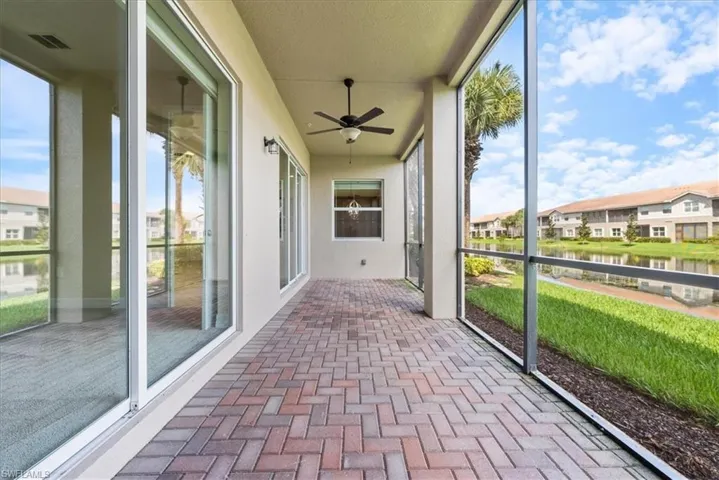 Unfurnished sunroom with a wealth of natural light, ceiling fan, and a water view