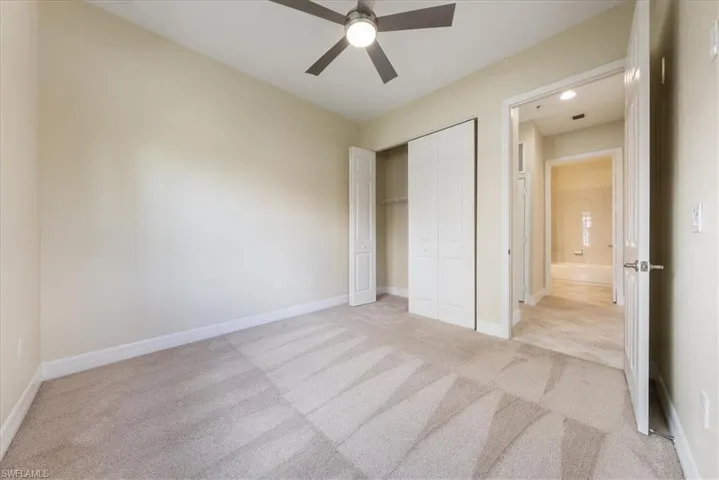 Unfurnished bedroom featuring light colored carpet, ceiling fan, and a closet