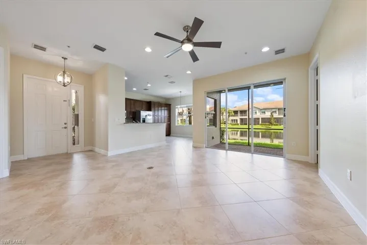 Unfurnished living room with ceiling fan with notable chandelier and light tile patterned floors