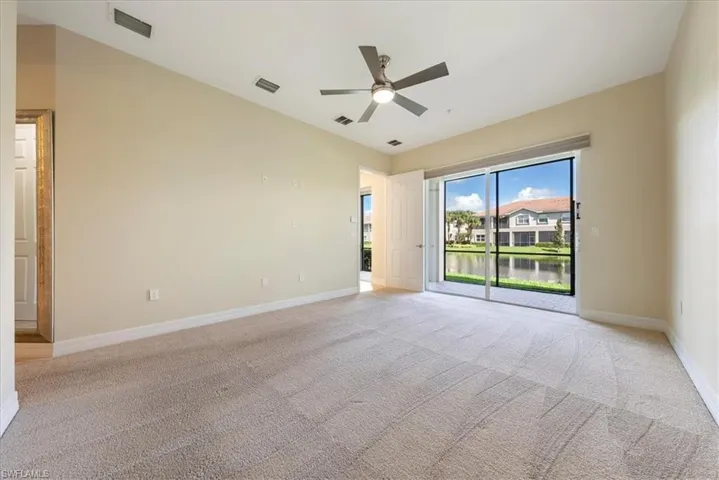 Carpeted empty room featuring ceiling fan and a water view