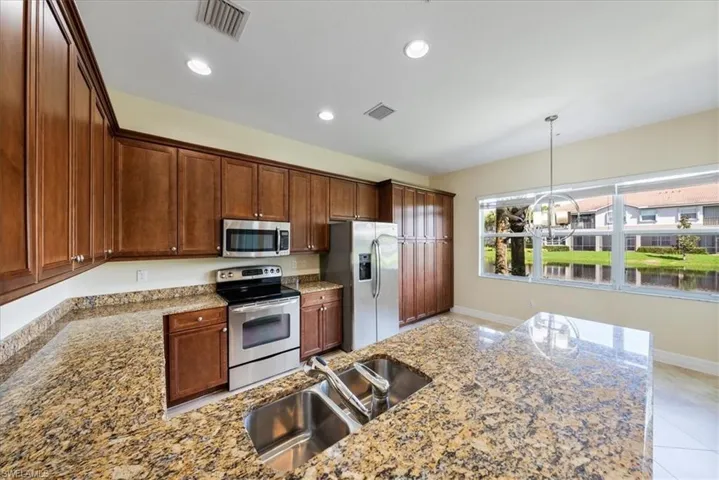 Kitchen with light stone countertops, light tile patterned floors, stainless steel appliances, and sink