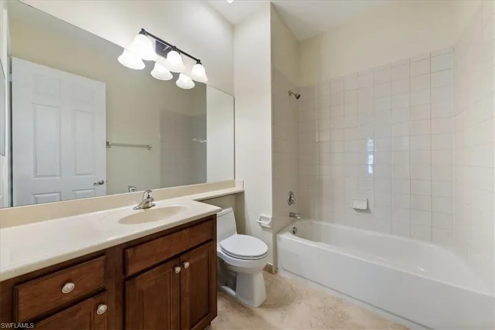 Full bathroom with tiled shower / bath, vanity, and toilet