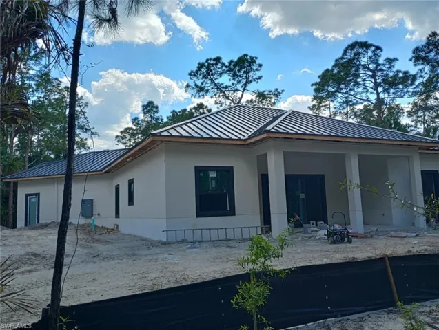 Rear view of house featuring stucco siding, a metal roof, and a patio