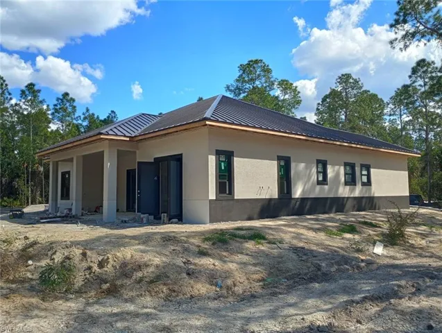 View of side of property with stucco siding and a metal roof