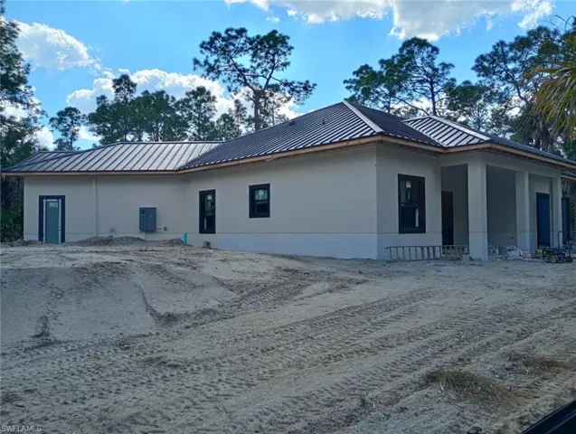 View of side of property featuring stucco siding and a standing seam roof