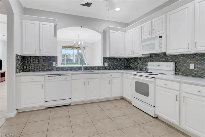 Kitchen featuring white appliances, a sink, white cabinets, and crown molding