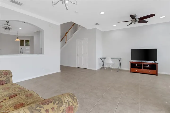Tiled living room featuring ornamental molding, visible vents, and a ceiling fan