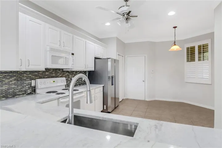 Kitchen with white appliances, a sink, backsplash, and light tile patterned floors