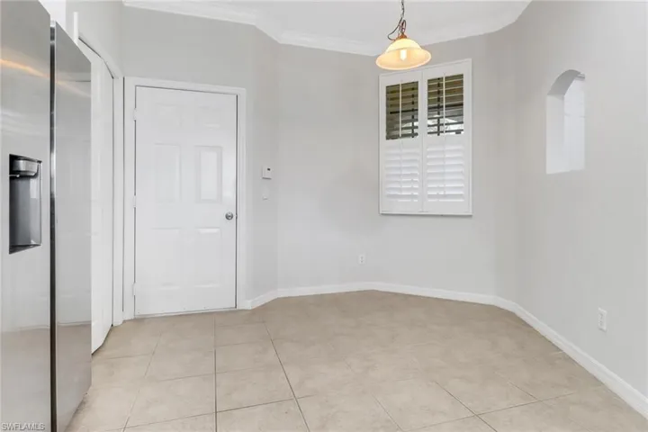 Spare room featuring baseboards, light tile patterned flooring, arched walkways, and crown molding