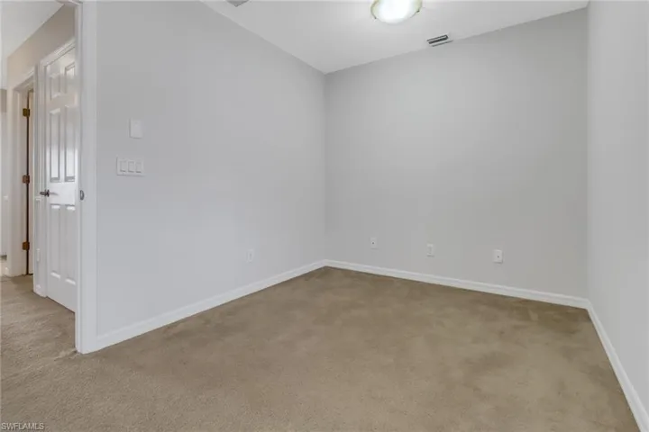 Carpeted empty room with visible vents and baseboards