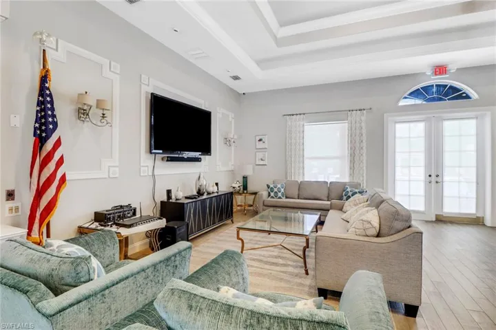 Living room with light hardwood / wood-style flooring, a raised ceiling, and french doors