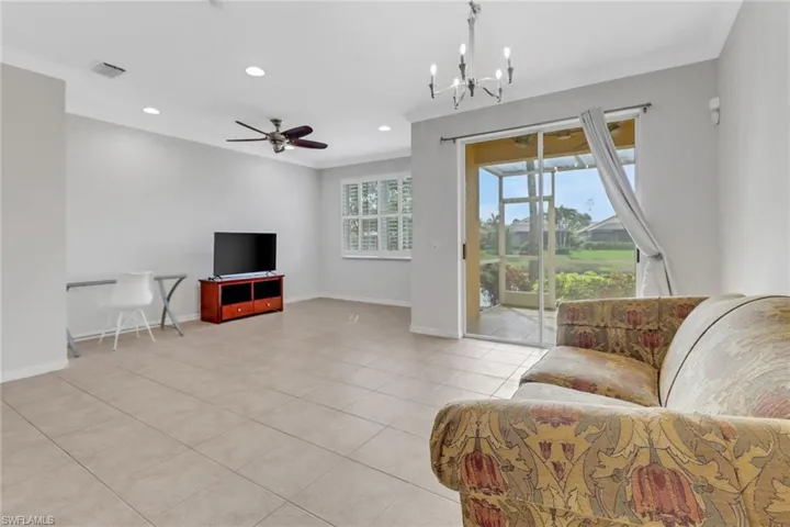 Living area featuring light tile patterned floors, recessed lighting, ornamental molding, baseboards, and ceiling fan with notable chandelier