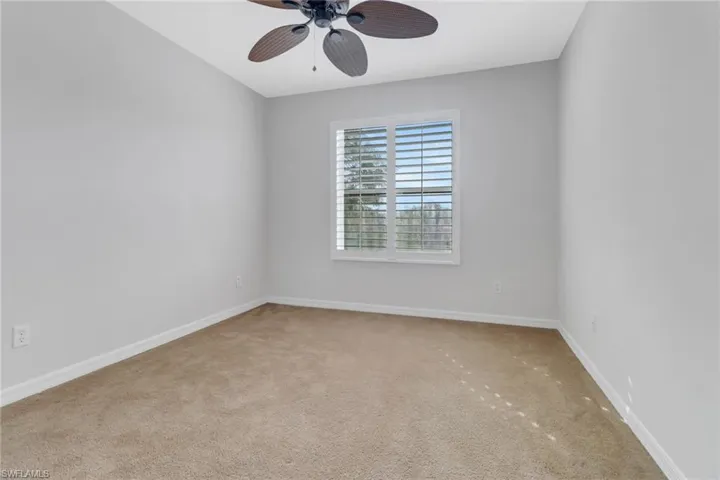 Carpeted spare room featuring a ceiling fan and baseboards