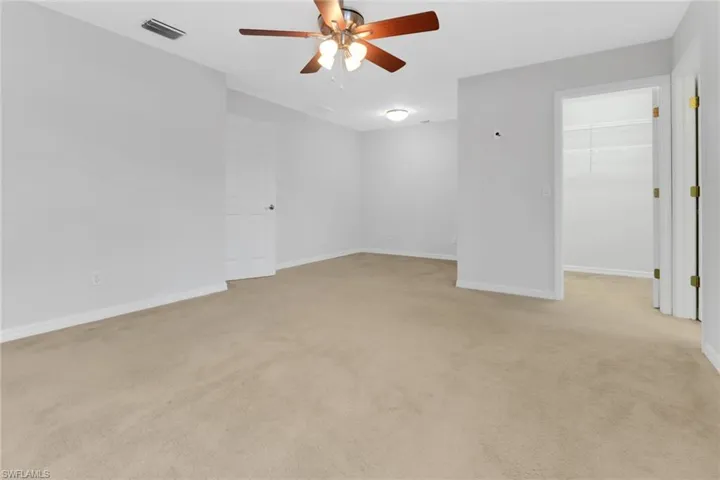 Spare room featuring visible vents, ceiling fan, light carpet, and baseboards