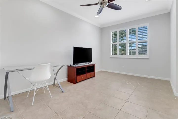 Office area with baseboards, ornamental molding, a ceiling fan, and light tile patterned flooring