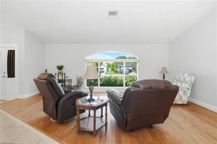 Living area featuring a large arched window, light wood-finish flooring, and light-toned walls