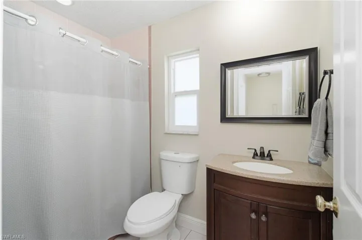 Bathroom featuring a dark wood vanity with a light-toned countertop, a framed mirror, and a window