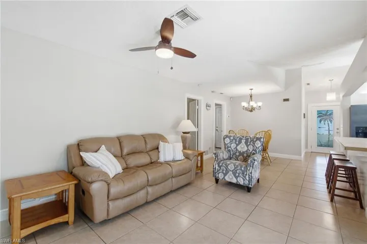 Open-concept living space featuring neutral tone walls, square tile flooring, a ceiling fan with integrated lighting, and recessed lighting