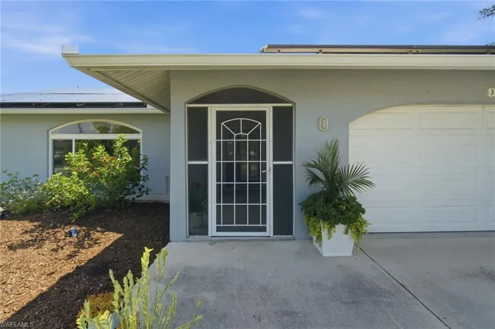Front exterior with arched entry, screen door, and a two-car garage